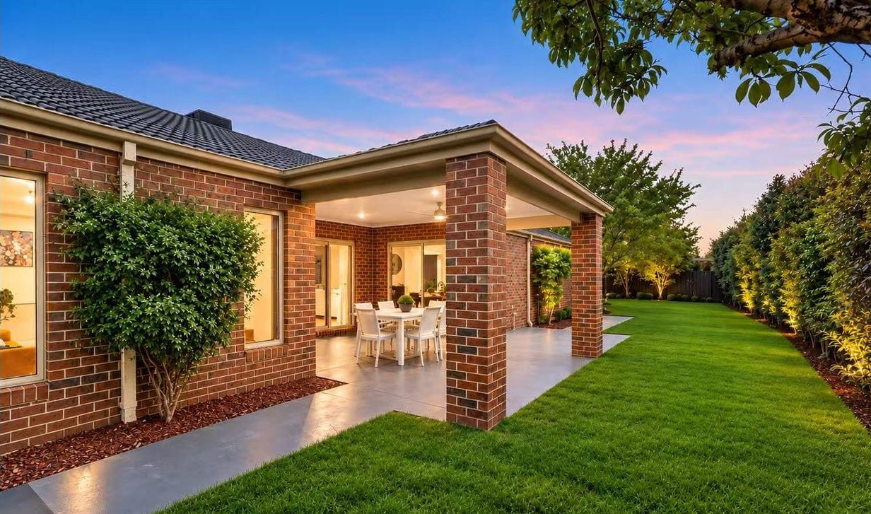 Exterior rear view of the home at dusk showing the covered alfresco and expansive green lawn